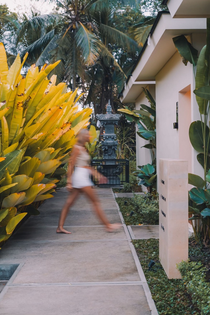 Holly walking along a garden path past bright yellow leaves at a Bali resort