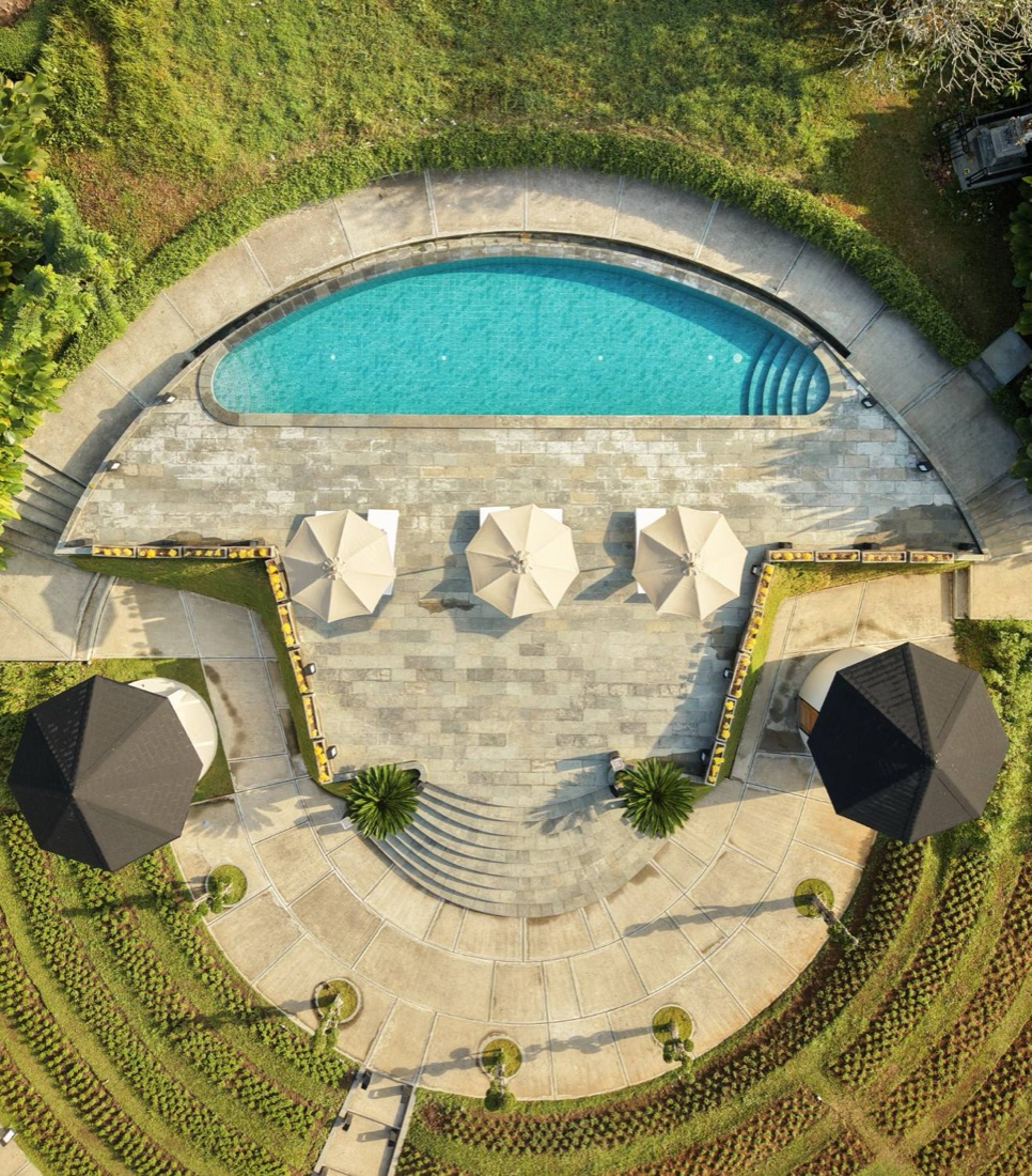 Drone view of a curved resort pool with three parasols